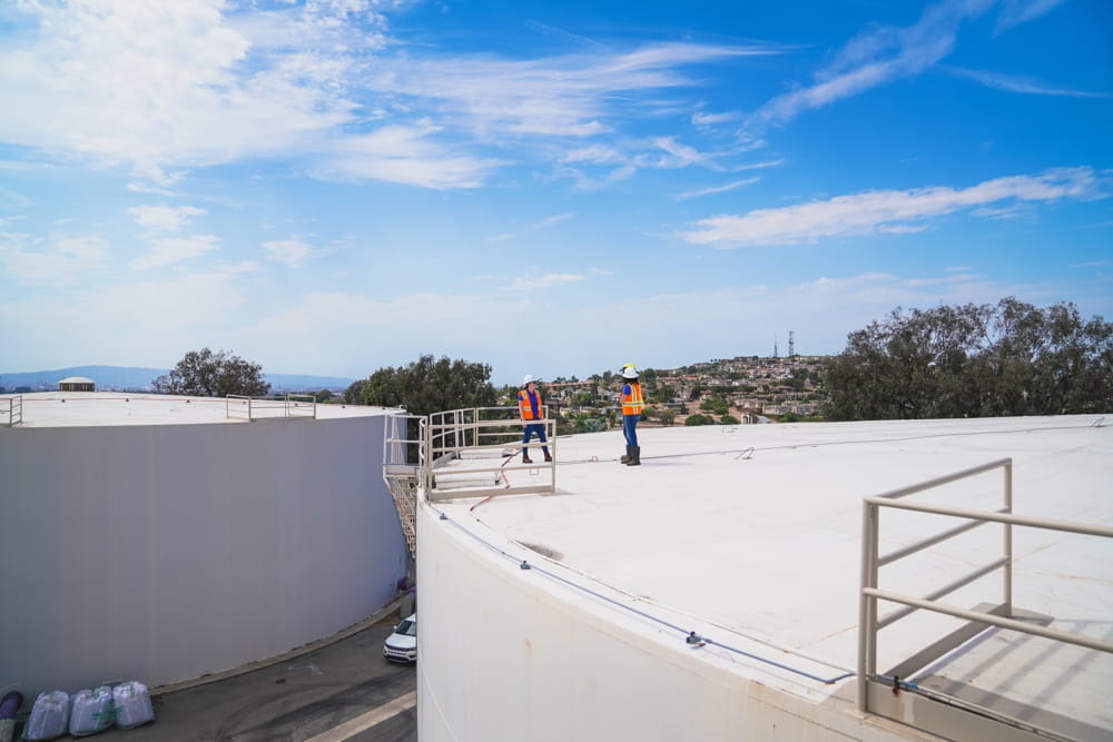 LBU workers on top of large water container.