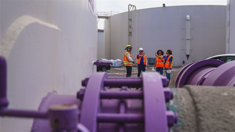 water tank with purple pipe fitting and worker in the background