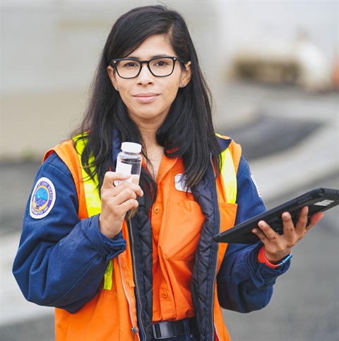 Woman in safety vest holding water sample