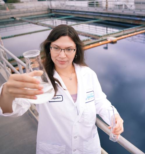 Photo of Long Beach Utilities Employee Holding Up a Glass Cylinder of Drinking Water